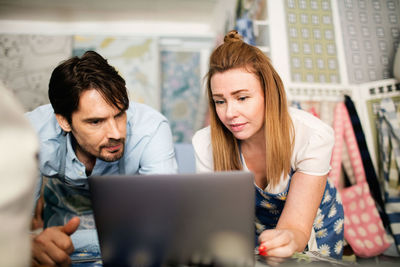 Male and female owners using laptop in fabric shop