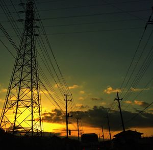 Low angle view of electricity pylon against sky at sunset