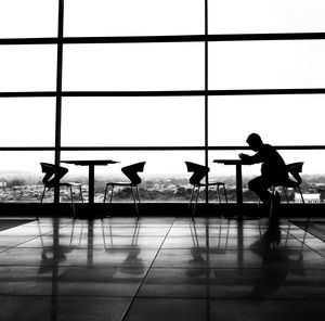 Silhouette people at airport against sky