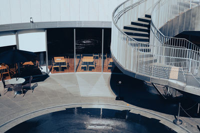 Empty chairs by water fountain against building