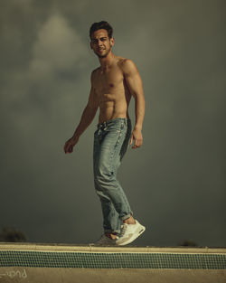 Portrait of shirtless man standing against wall