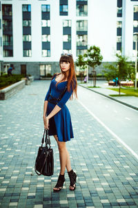 Full length portrait of young woman standing in city