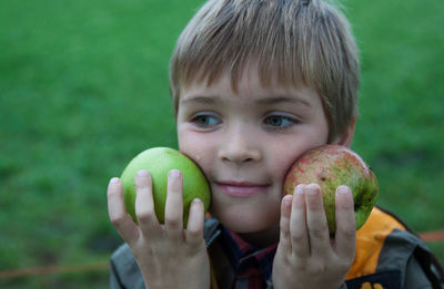 Close-up of boy holding apples on field