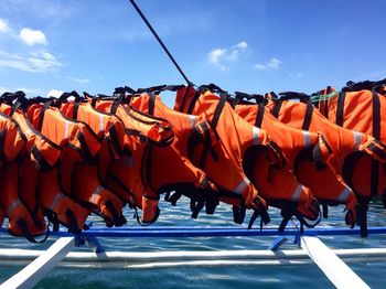 Life jackets drying on clothesline against sky