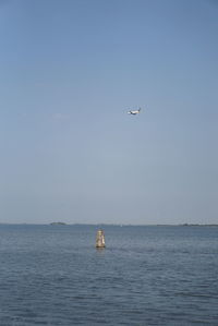Airplane flying over sea against sky