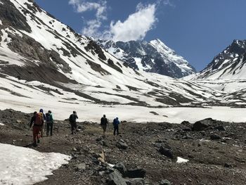 People walking on snowcapped mountain against sky