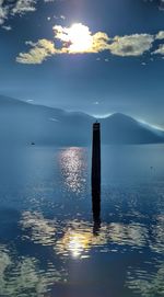 Wooden posts in sea against sky during sunset