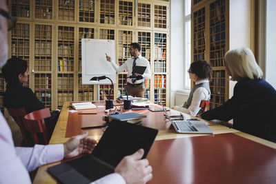 Male professional giving presentation to coworkers in board room