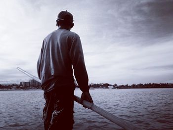 Rear view of man standing in river against sky