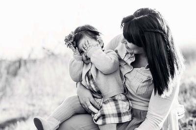 Rear view of mother and daughter sitting outdoors