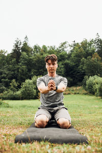 Young man doing exercises outside on grass during his calisthenics workout outdoors