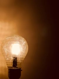 Close-up of illuminated light bulb against wall