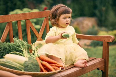 Happy girl sitting on bench against plants