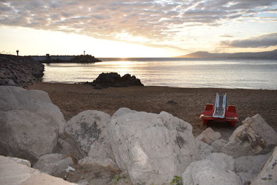 Rocks on beach against sky during sunset