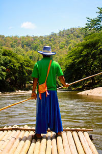 Rear view of man standing by lake against sky