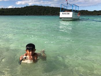 Boy in sea against sky