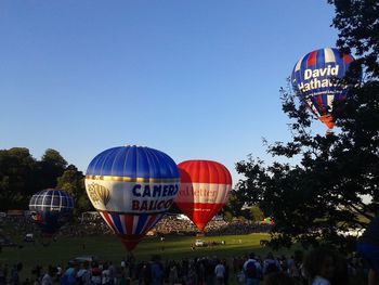 People at amusement park against clear blue sky