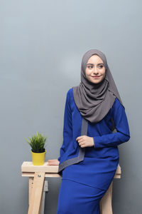 Portrait of young woman standing against white background