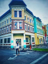 Full length of woman standing on street against building in city