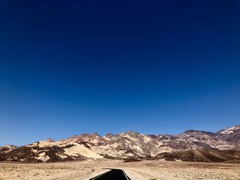 Scenic view of desert against clear blue sky