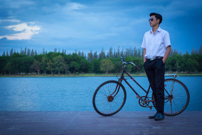 Man riding bicycle on water against sky