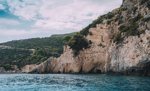 Scenic view of sea by mountain against sky