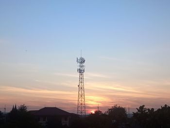 Low angle view of electricity pylon against sky during sunset