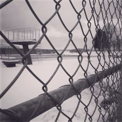 Snow covered field seen through chainlink fence