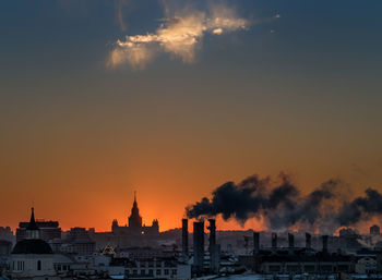 Smoke emitting from chimney at factory against sky during sunset