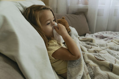 Portrait of little girl blowing her nose