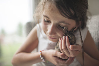 Close-up of girl holding bunny while sitting at home