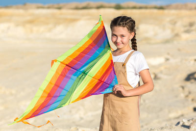 A girl in a summer dress launches a kite into the sky wild.