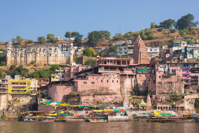 Houses by river against buildings in city