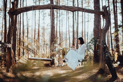 Rear view of woman sitting in the forest