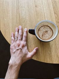 Hand holding coffee cup on table