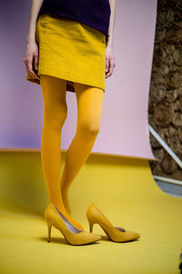 Low section of woman standing in yellow shoes