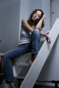 Young woman sitting on steps at home