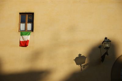 Low angle view of electric lamp and italian flag hanging on wall