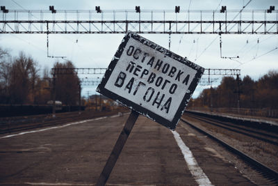 Signboard on railroad station platform against sky