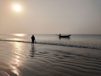 Silhouette man on beach against sky during sunset