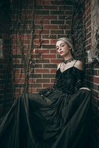 Portrait of woman standing against brick wall