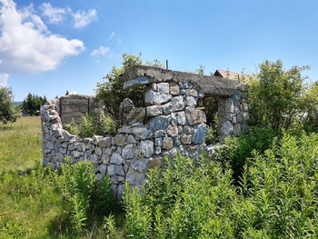 Old stone wall on field against sky