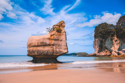 Rock formation on beach against sky