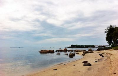 Scenic view of beach against cloudy sky