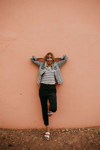 Portrait of young woman standing against wall