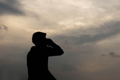 Silhouette woman standing against sky during sunset