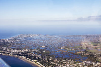 Aerial view of city by sea against sky