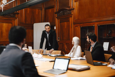 Businessman discussing with colleagues in board room during conference meeting