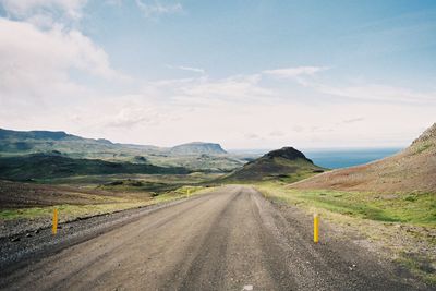 Road leading towards mountains against sky