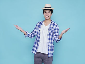 Portrait of young man standing against blue background